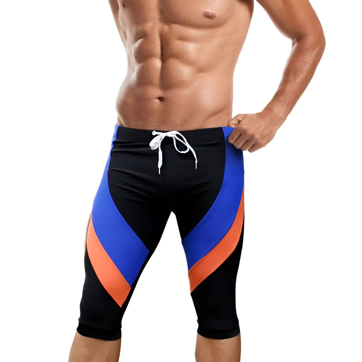 Pantalon de sport orange et noir avec détails réfléchissants jaunes, idéal pour le running ou le cyclisme. Coupe ajustée, tissu technique respirant.