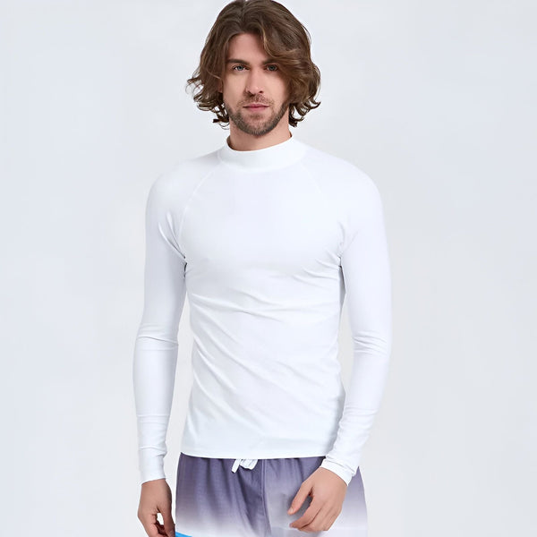 Un homme portant un rashguard de surf noir et gris à manches longues et un short de bain bleu.