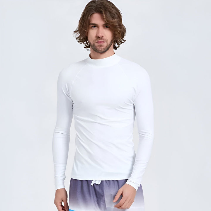 Un homme portant un rashguard de surf noir et gris à manches longues et un short de bain bleu.