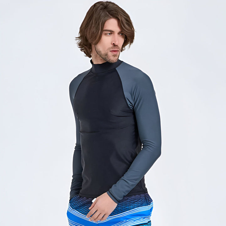 Homme en rash guard bleu avec un short de bain à rayures colorées. Vêtements de plage pour la protection solaire. Mode estivale, look décontracté.