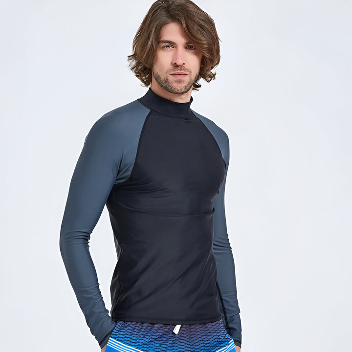 Homme portant un rashguard blanc à manches longues et un short de bain dégradé bleu et gris. Vêtements de plage pour la protection solaire.