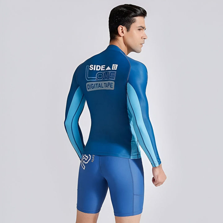 Homme portant un rashguard bleu et un short de bain assorti. L'ensemble est orné d'un motif "Side A/B Love Digital Tape" au dos du maillot.