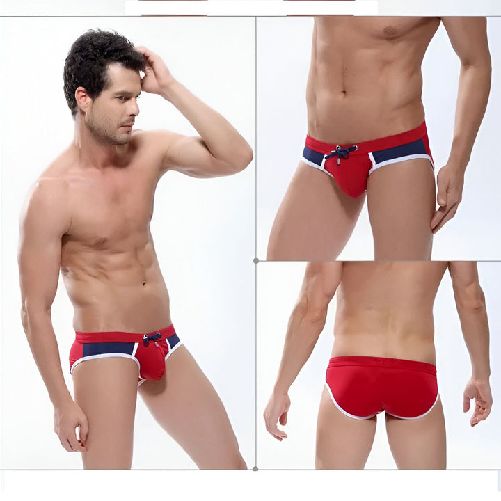 Homme torse nu en slip de bain bleu marine, rouge et blanc. Cordon de serrage rouge. Abdominaux visibles. Corps athlétique. Mode masculine, maillot de bain.