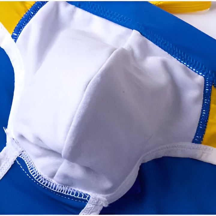 Homme en maillot de bain jaune et bleu, posant. Sous-vêtement de bain masculin, collection été. Mode plage, vêtement de bain pour homme. Accessoire de mode estivale. Corps masculin athlétique.