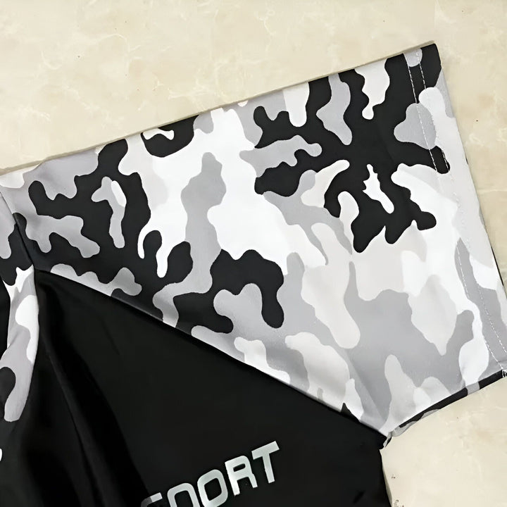 Un homme portant un ensemble de bain noir et camouflage avec des lunettes de soleil devant une piscine et des palmiers. Vêtements de bain pour homme, style vacances.