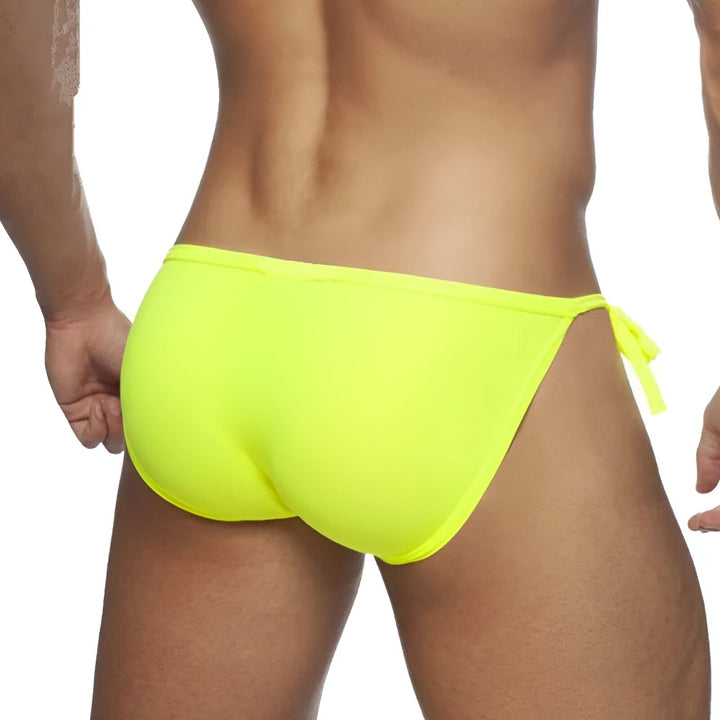 Image d'un slip de bain pour homme de couleur vert fluo avec des cordes sur les côtés et une doublure blanche.