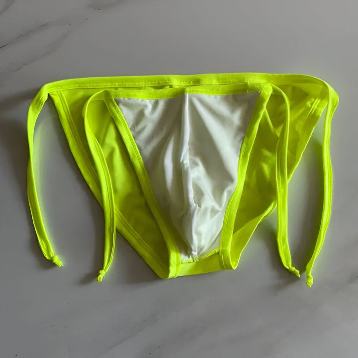 Vue arrière d'un homme portant un slip de bain jaune vif avec des cordons sur le côté. Le corps est musclé et bronzé.