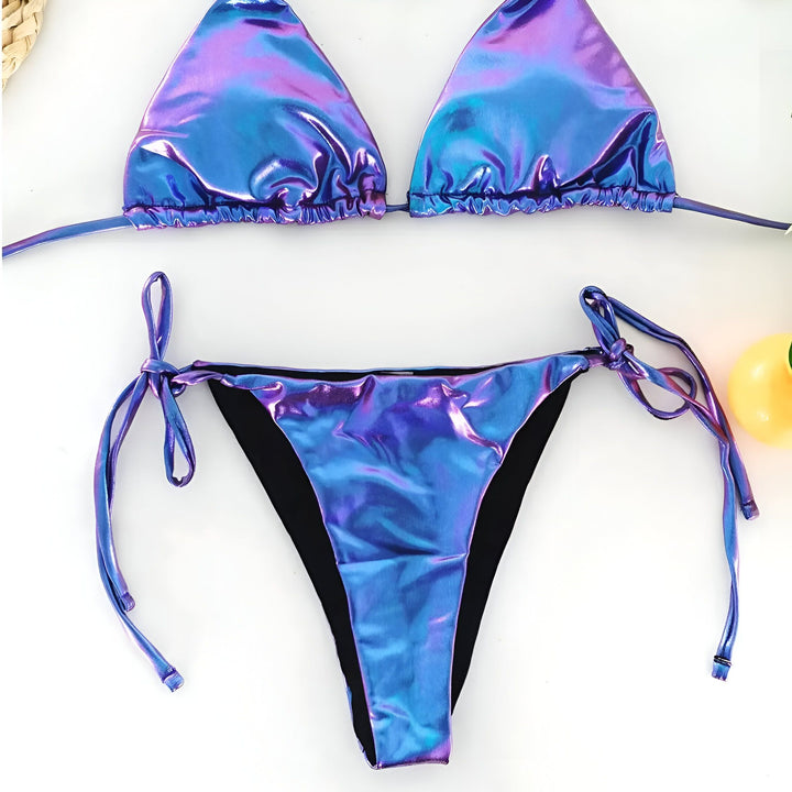 Maillot de bain deux pièces bleu iridescent sur un livre avec une branche de plante et un chapeau de paille avec un papillon rose dessus. Vêtements d'été pour la plage ou la piscine.
