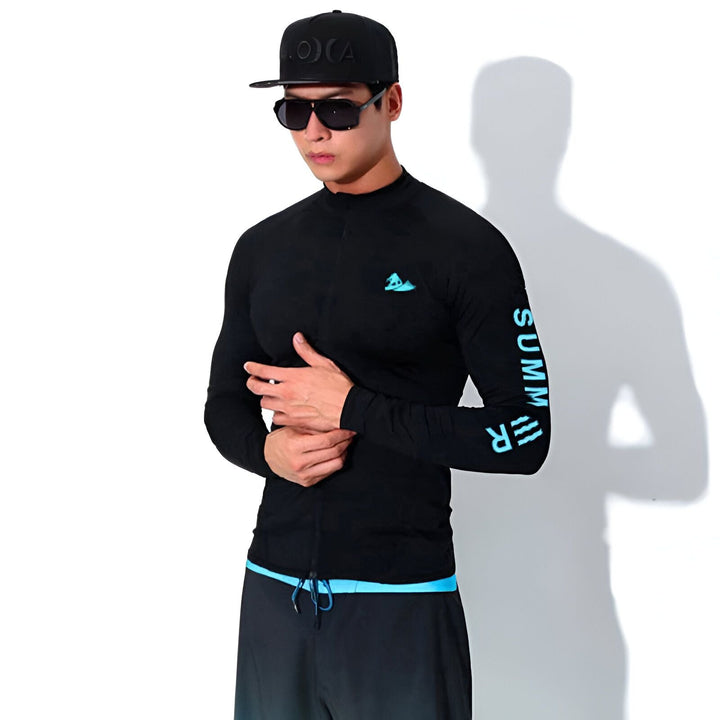 Homme en tenue de plage noire avec détails bleus : haut à manches longues, short dégradé, casquette et lunettes de soleil. Style sportif et moderne.