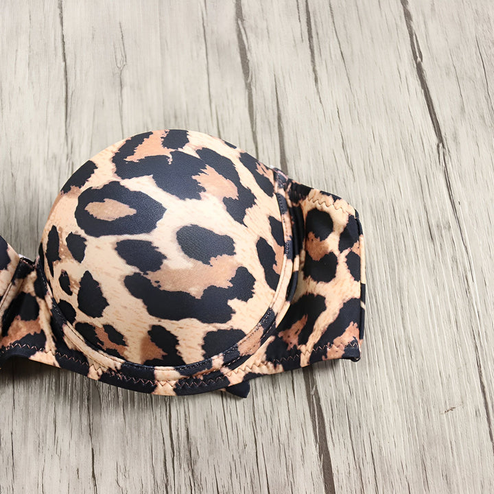 Maillot de bain deux pièces à motif léopard sur un fond en bois. Haut bandeau et culotte échancrée assortis. Bretelles fines. Mode été, vêtements de plage.