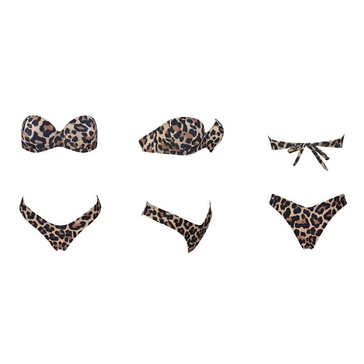 Une jeune femme en bikini léopard, assise devant des plantes tropicales, baignée de lumière naturelle, peau bronzée, tatouages visibles, regard intense, ambiance estivale et exotique.