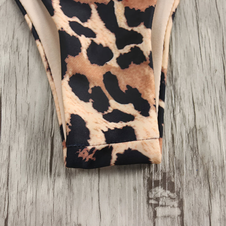 Gros plan sur un tissu imprimé léopard beige et noir, partiellement plié, sur un fond de bois clair texturé.