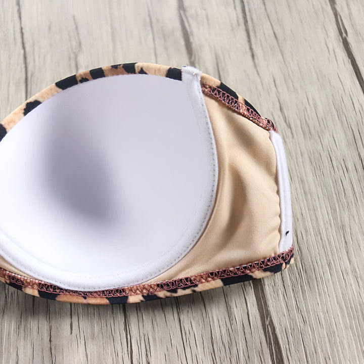 Culotte de bikini échancrée avec motif léopard sur fond bois clair. Mode été, maillot de bain tendance, imprimé animal, vêtement de plage.