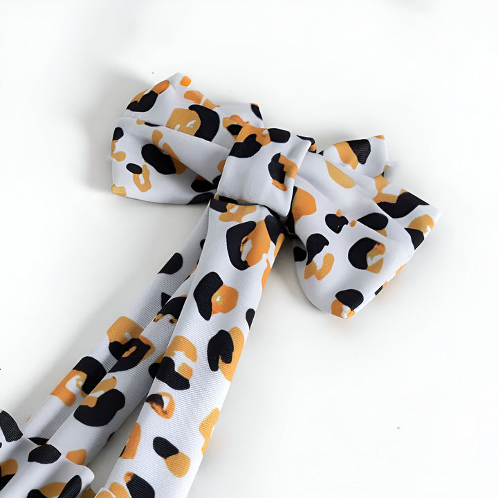 Serre-tête à motifs léopard noir et ocre sur fond blanc. Accessoire cheveux tendance.