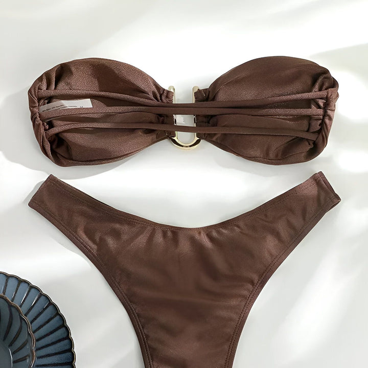 Image d'un bikini marron deux pièces avec un haut bandeau et une boucle dorée, posé sur un fond blanc. Idéal pour la plage ou la piscine, ce maillot de bain offre style et confort.