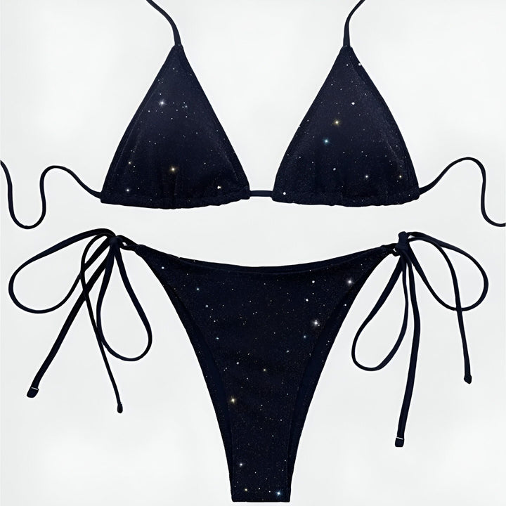 Une femme portant un bikini noir scintillant. La peau de la femme présente des tatouages sur les bras.