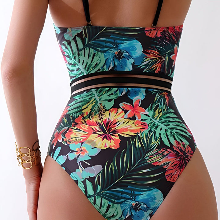 Maillot de bain une pièce noir à motifs floraux colorés et feuilles tropicales. Bretelles fines noires et bordure unie noire. Parfait pour la plage ou la piscine. Mode été.