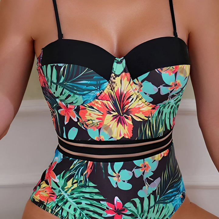 Motif floral tropical sur tissu noir et bleu. Gros plan sur une fleur bleue avec des feuilles vertes. Détail de couture.