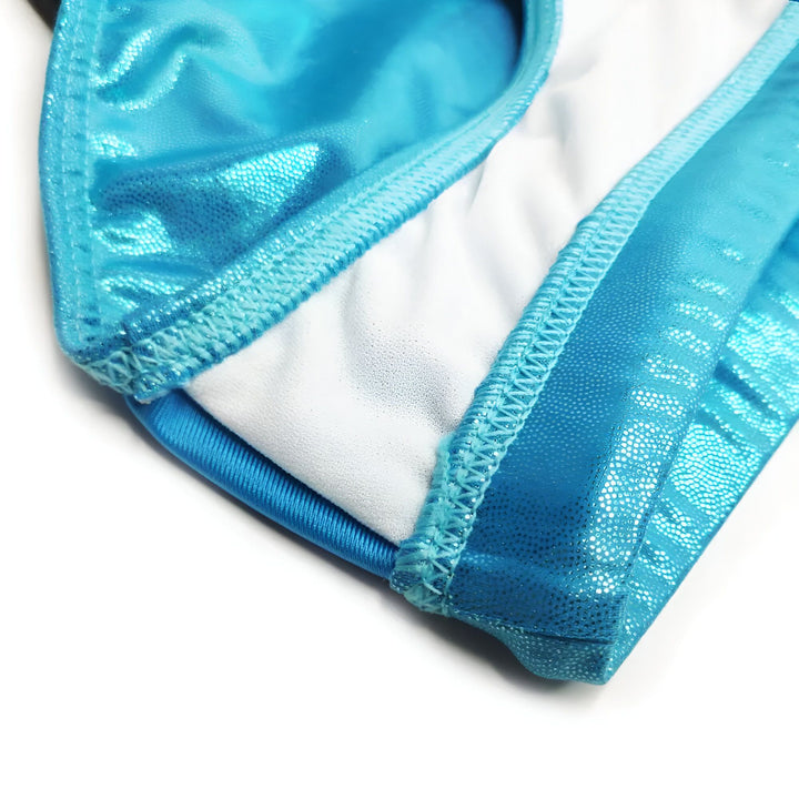 Homme musclé torse nu portant un slip de bain noir avec une prothèse de contour en mousse. Tatouages visibles sur les bras. Mise en valeur de l'apparence masculine et accessoires de mode masculine.