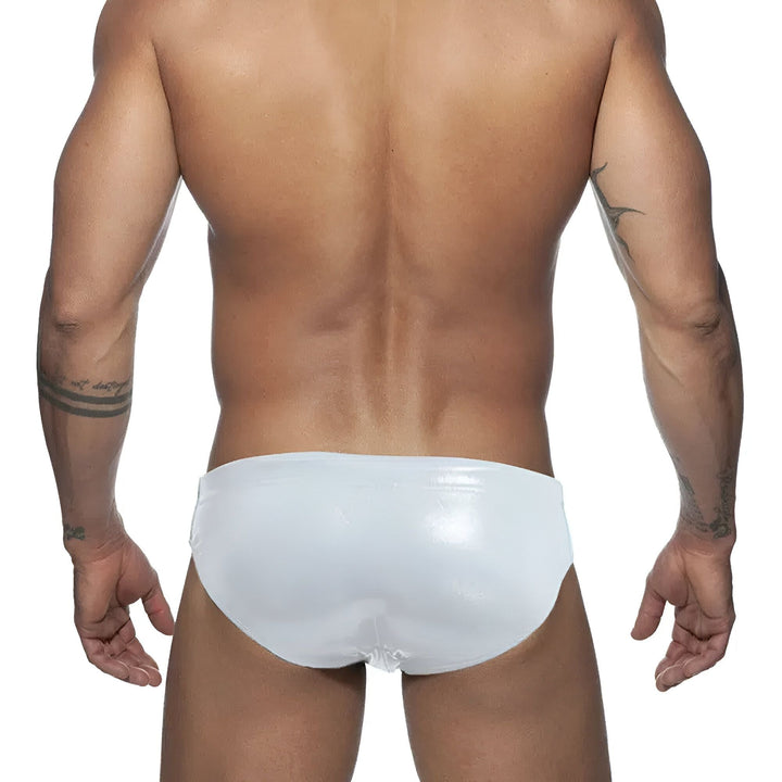 Homme musclé portant un slip rouge brillant avec coque amovible. Tatouages visibles sur les bras. Torse athlétique. Sous-vêtement masculin de mode.