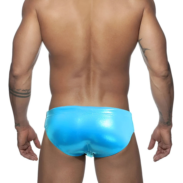 Homme musclé en slip blanc avec une protection pénienne amovible. Tatouages sur les bras et le torse. Sous-vêtement masculin pour la plage ou la piscine.