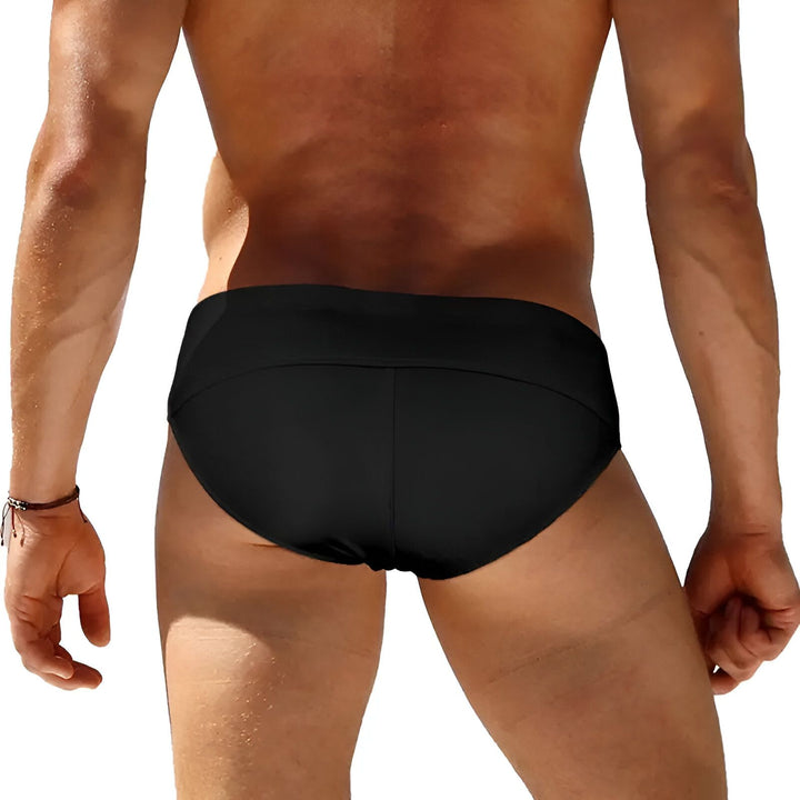 Homme en slip de bain blanc avec anneaux métalliques. Torse musclé et peau bronzée. Sous-vêtement de mode masculine. Corps masculin athlétique. Vêtements d'été pour homme.