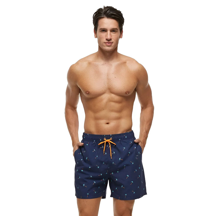 Gros plan sur un short de bain bleu marine avec un motif de palmiers et un cordon de serrage orange.