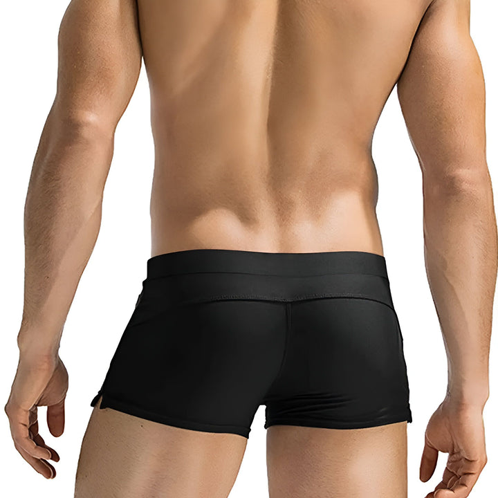 Homme torse nu portant un slip de bain bleu marine avec des poches zippées. Cordon de serrage noir avec œillets dorés. Corps athlétique et musclé. Idéal pour la plage ou la piscine. Mode masculine estivale.