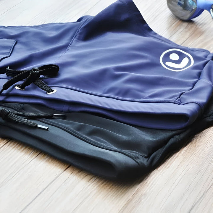 Gros plan d'un caleçon de bain bleu marine avec un cordon noir. Une poche zippée contient un smartphone.