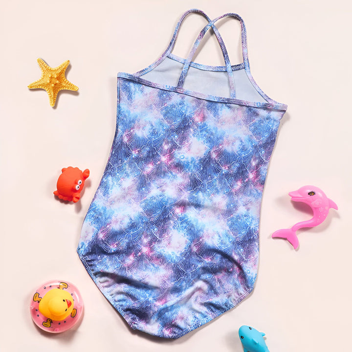 Détail du dos d'un maillot de bain enfant imprimé écailles. Bretelles croisées violettes, bleues et roses. Couture apparente. Fond uni beige.