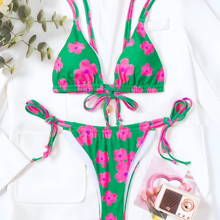 Gros plan d'une femme portant un bikini vert à fleurs roses, mettant en valeur sa silhouette et le motif estival. Idéal pour la mode de plage et les tendances estivales.