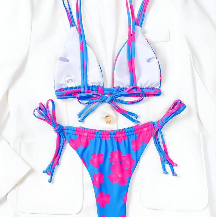 Femme portant un bikini vert à motifs floraux roses. Le maillot de bain deux pièces met en valeur son ventre bronzé. Accessoires : collier de perles. Idéal pour la plage ou la piscine.