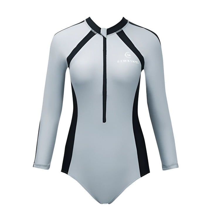 Femme portant un maillot de bain gris et noir à manches longues avec fermeture éclair, une visière grise et des tresses décorées. Idéal pour la natation et les sports nautiques.