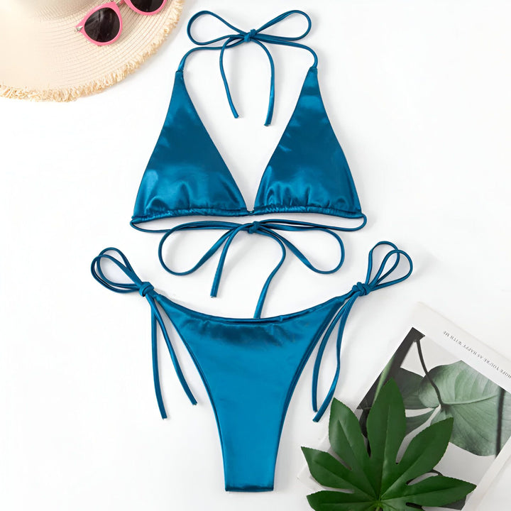Image d'un bikini noir deux pièces en satin, avec un haut triangle à nouer dans le cou et un bas assorti à fines lanières latérales. Mode de bain.