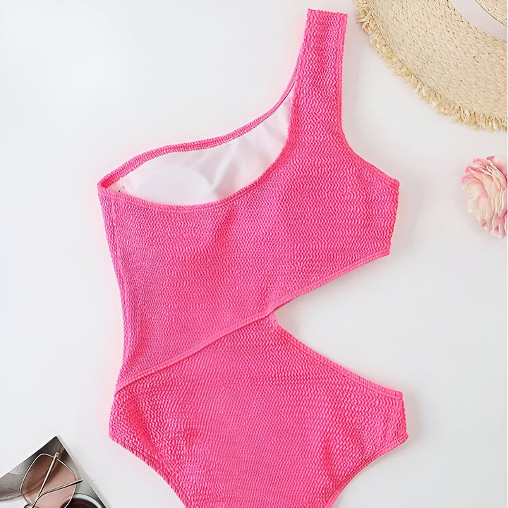 Vue arrière d'une femme portant un maillot de bain noir une pièce asymétrique avec découpe latérale.