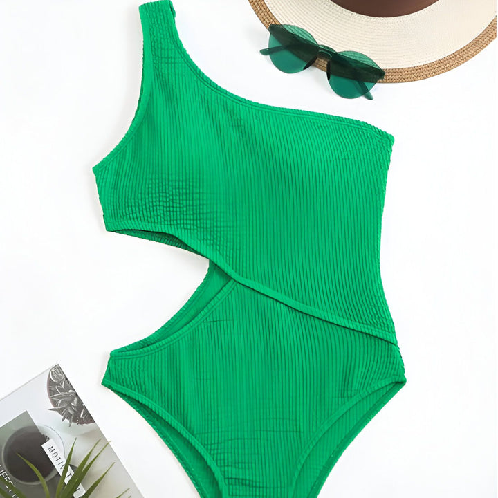 Image d'un maillot de bain une pièce violet texturé avec une découpe, à côté d'un chapeau de paille, d'une fleur jaune et d'un livre. Mode d'été, vêtements de plage, style estival.