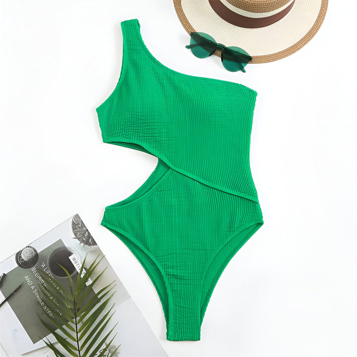 Image d'un maillot de bain vert vif une pièce, asymétrique, avec une découpe à la taille, un chapeau de paille, un tournesol et un livre blanc intitulé Romance.