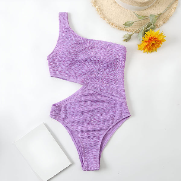 Maillot de bain une pièce vert à une épaule, lunettes de soleil vertes et chapeau de paille sur fond blanc. Vêtement d'été tendance et élégant.