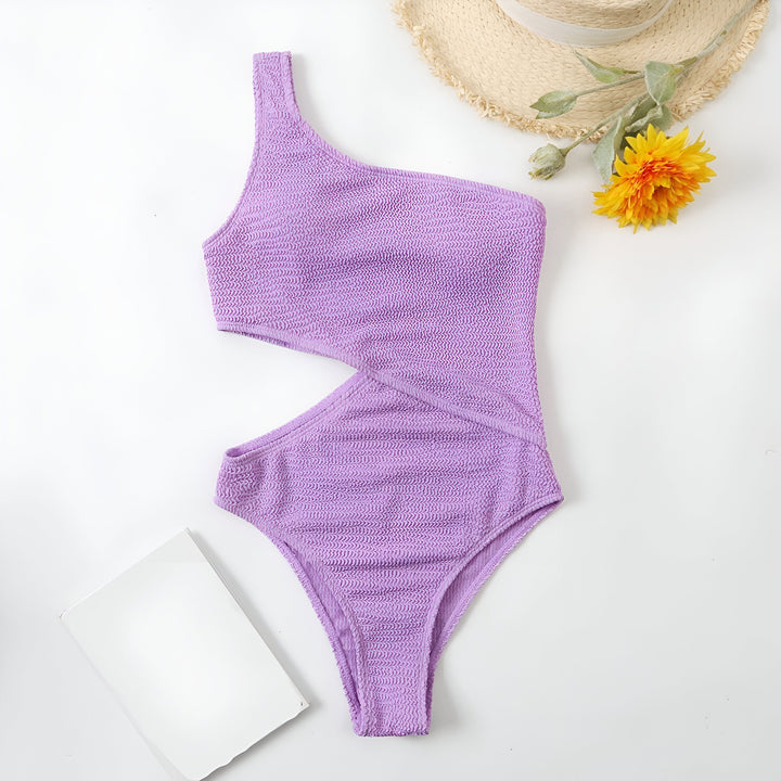 Maillot de bain une pièce vert à une épaule, lunettes de soleil vertes et chapeau de paille sur fond blanc. Vêtement d'été tendance et élégant.