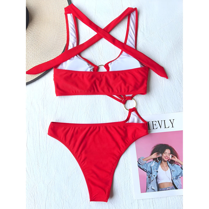 Maillot de bain noir une pièce avec découpes et anneaux dorés, accompagné d'un chapeau de paille et de tongs décorées de marguerites. Tenue de plage féminine et élégante.