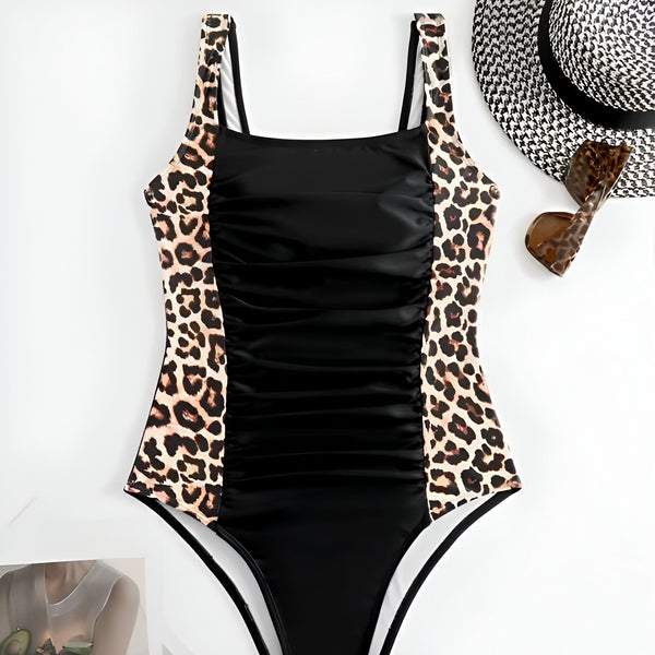 Vue arrière d'une femme portant un maillot de bain une pièce noir et un bracelet doré. Plante verte en arrière-plan. Mode estivale, prêt-à-porter féminin.