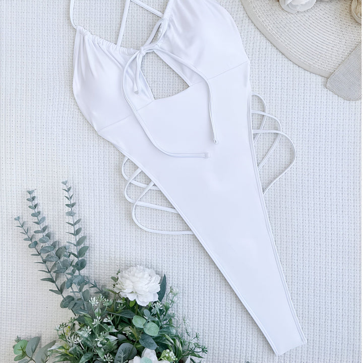 Gros plan d'une femme portant un maillot de bain une pièce blanc avec des détails noués et un paréo assorti.