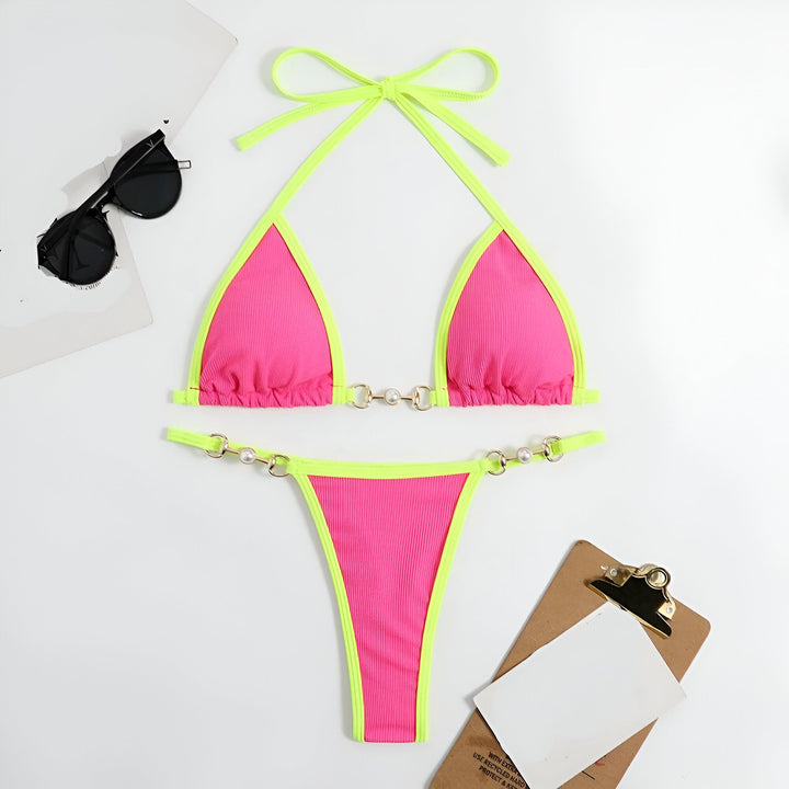 Femme en bikini orange et turquoise sur une plage de sable blanc. L'océan turquoise et le ciel bleu sont visibles en arrière-plan. Style estival, mode balnéaire.