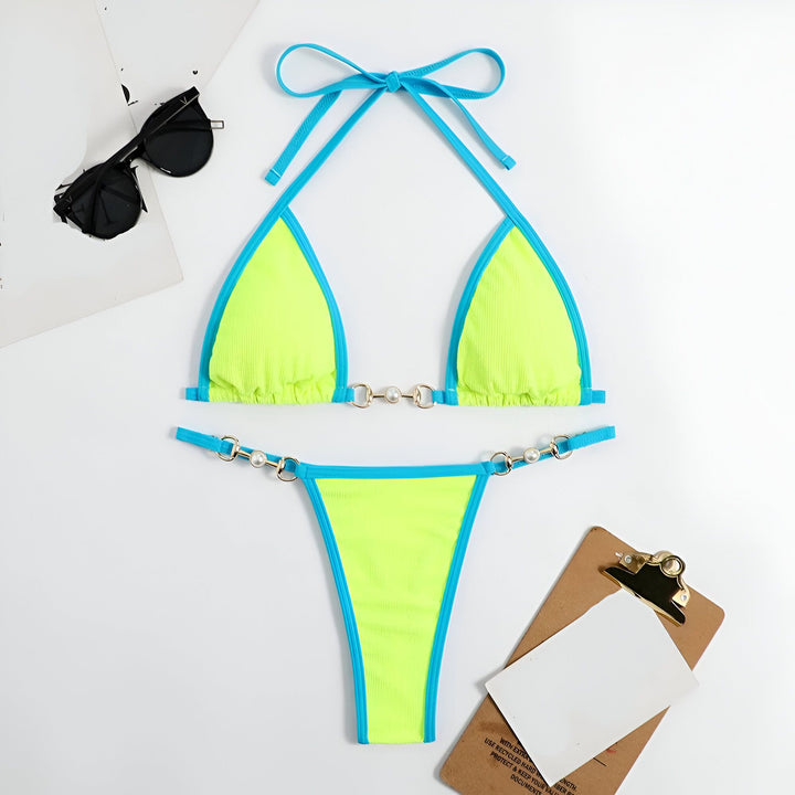 Femme en bikini jaune et orange sur une plage ensoleillée. L'océan turquoise est visible en arrière-plan. Sable blanc et ciel bleu clair complètent le paysage.