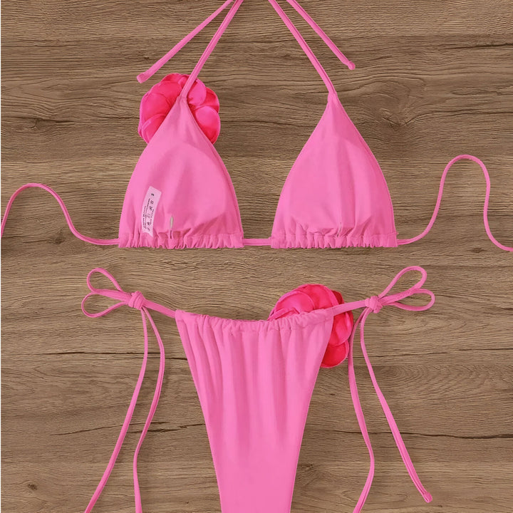 Haut de bikini rouge avec des détails de roses, agencé avec un chapeau de paille et des lunettes de soleil roses sur une table en bois. Élégance estivale.