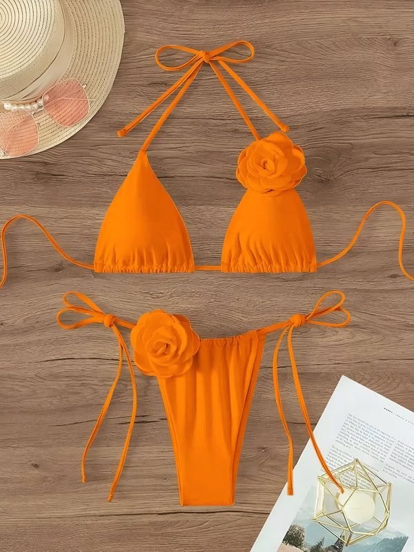 Maillot de bain orange avec ornements floraux, chapeau de paille et lunettes de soleil sur une table en bois pour la plage et le soleil d'été. Mode et vacances.