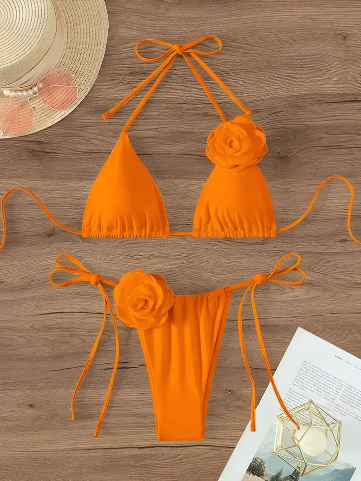 Maillot de bain orange avec ornements floraux, chapeau de paille et lunettes de soleil sur une table en bois pour la plage et le soleil d'été. Mode et vacances.