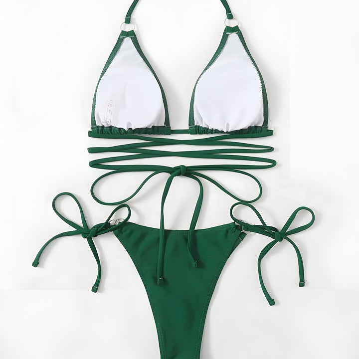 Femme portant un bikini vert émeraude avec des liens croisés sur le ventre et des détails dorés.
