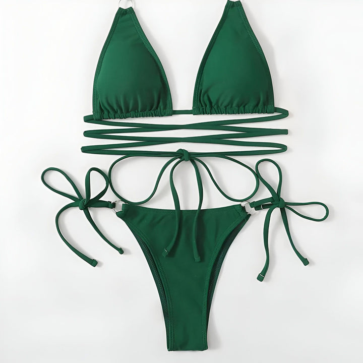 Une femme portant un bikini triangle vert fluo avec une chaîne en or et un pendentif représentant l'Afrique. Le bikini a des détails à anneaux argentés et des liens croisés autour de la taille.