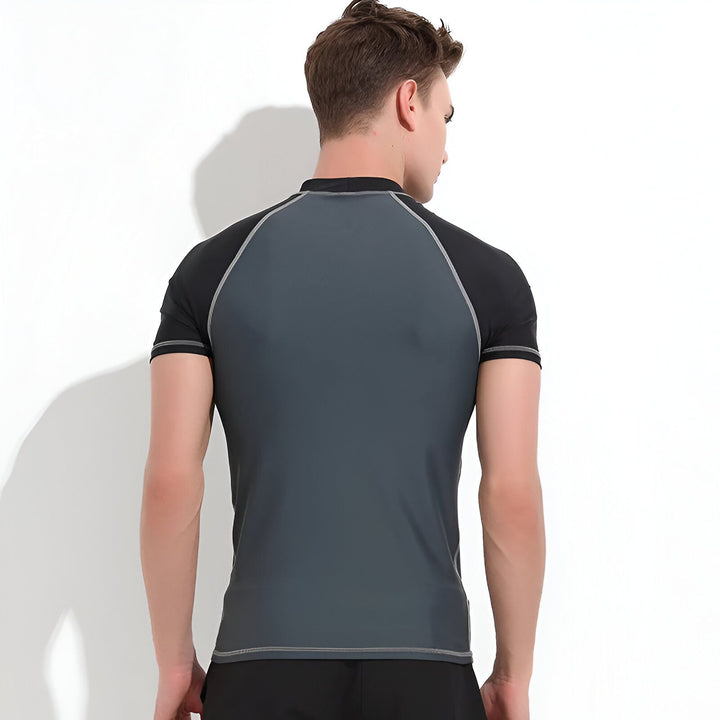 Homme portant un rashguard bleu et marine à manches courtes et un short de bain marine. Vêtements de plage pour homme.